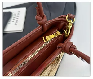 Detail of smooth gold zipper and hardware on brown leather and straw bucket bag