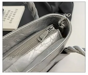 Macro detail of the smooth silver metal zipper and pleated texture on the bucket bag