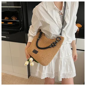 Detail of woven straw shoulder bag with marble bead handle and crossbody strap