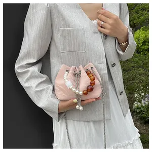 Detalle de bolso saco rosa con cordón y asa decorativa de perlas y cuentas de ámbar