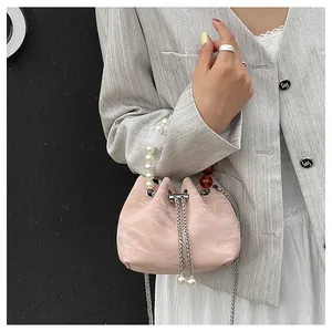 Detalle de bolso cubo rosa con textura de mármol, asa de perlas y correa de cadena