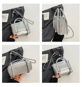 Detail view of silver pleated bucket bag showing rope handles and metallic chain strap