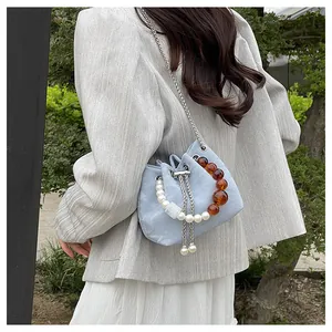 Detalle del bolso de cubo azul claro con cuentas de perlas y correa de cadena