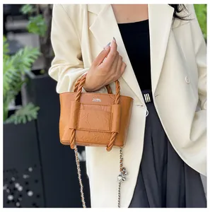 Close-up of textured camel bucket bag with twisted handle and silver chain detail