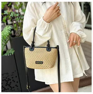 Detailed view of straw bucket bag with black leather straps and fashion metal logo plate