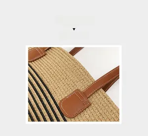 Close-up of handwoven straw tote bag featuring brown leather trim and detailed white stitching