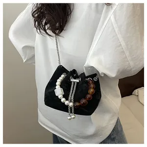 Detalle del bolso de terciopelo negro con asa de perlas grandes y cuentas de ámbar