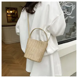Dettaglio borsa a secchiello in paglia intrecciata a mano con texture naturale e cuoio