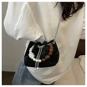Detalle del bolso de hombro tipo cubo negro para mujer con asa de perlas y cuentas ámbar
