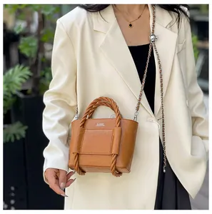 Brown pleated tote bag with braided handle and silver chain strap worn by a model