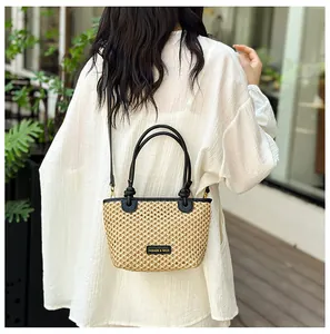 Detail of woven straw bucket bag with black leather straps and metal fashion logo