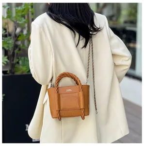 Detail of caramel brown bucket bag with twisted rope handles and classic gold chain strap