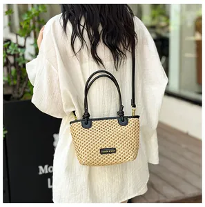 Detail of hand-woven straw bucket bag with black leather trim and adjustable shoulder strap