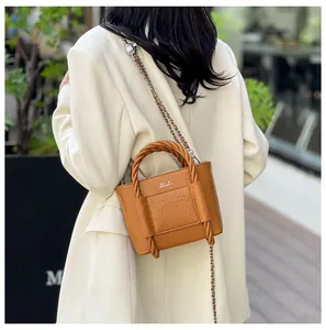 Detail of caramel brown crossbody bag with woven handle and classic lettering print