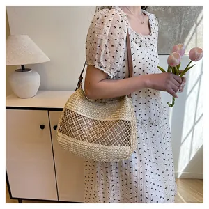Dettaglio della borsa in paglia beige con trama a rete e tracolla in pelle elegante