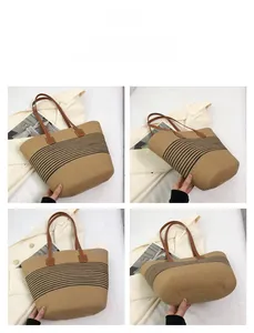 Detail view of woven straw tote bag featuring black stripes and brown leather straps