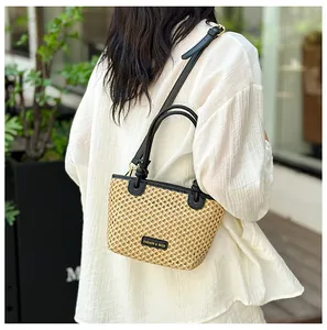 Close-up of woven mini bucket bag with black leather trim worn on model's shoulder