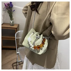 Detalle de bolso tipo cubo verde menta con asa de perlas y correa de cadena metálica