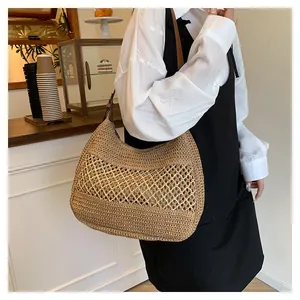 Dettaglio borsa a spalla in paglia marrone con design traforato e tracolla in pelle scura