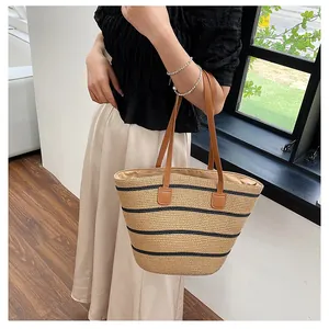 Close-up of a striped straw tote bag featuring brown leather handles and woven texture