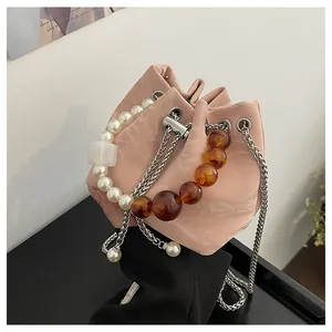 Detalle de bolso cubo mármol rosa con asa de perlas blancas y correa de cuentas ámbar