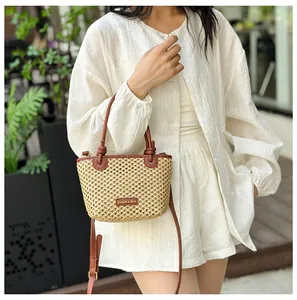 Detail of straw bucket bag with brown leather trim and FASHION & BAGS logo