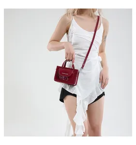 Dunkelrote Lackleder Mini-Tasche am Model mit weißem Modetext und verstellbarem Schultergurt