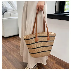 Detail of hand-woven straw tote with black stripes and brown faux leather handles