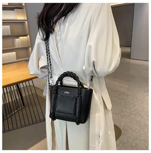 Close-up of black pleated tote bag with woven handle and silver chain strap detail