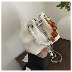 Detalle del bolso tipo saco blanco con textura de mármol, perlas y cadena de plata
