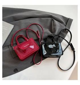 Detailansicht glänzender Lackleder-Minhandtaschen in Weinrot und Schwarz mit Griffen