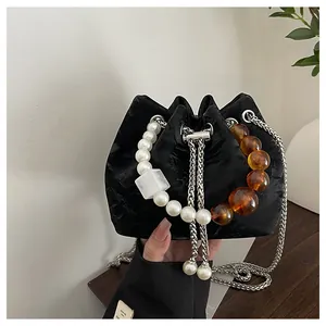 Detalle de bolso tipo cubo negro con grandes perlas y detalles de cuentas ámbar