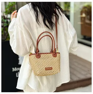 Outdoor street view of a woven straw bucket bag with leather handles and crossbody strap