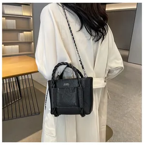 Detail view of black pleated texture mini tote bag with braided handle and silver chain strap