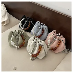 Detalle de bolsos bombonera coloridos con asas de perlas y correas de cadena plateada