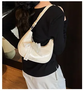 Detailed view of cream-white crescent hobo bag with pearl lace bow and heart charm