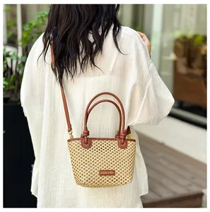 Close-up of woven straw bucket bag with leather strap and golden logo detail