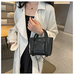 Detail showing black wrinkled texture tote with woven handles and metal chain strap