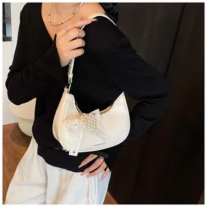 Detail of white moon bag with pearl beads and lace bow on shiny textured surface
