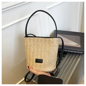 Detailopname van geweven strooien emmertas met visgraattextuur en zwart lederen handvat