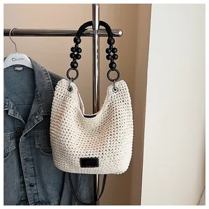 Chic off-white woven shoulder bag with beaded handle and contrast leather logo patch