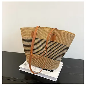 Detail of woven straw tote bag with black stripes and brown leather straps on a display