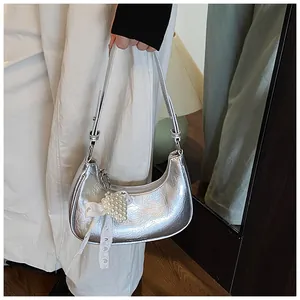 Close-up of metallic silver crescent bag with pearl heart charm and lace bow detail