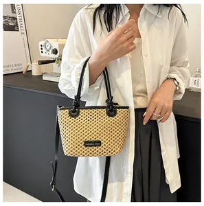 Detail of woven straw bucket bag featuring black leather handles and fashion logo