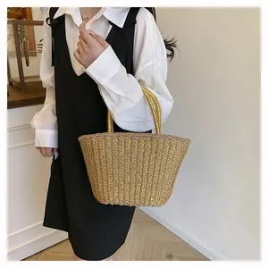 Détail d'un sac cabas tissé doré avec poignées arrondies pour un style de vacances