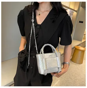 Detailed macro view of glossy silver metallic pleated leather handbag with chain strap