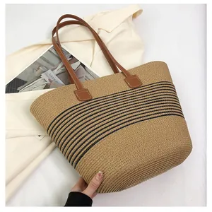 Detail of a striped straw tote bag with brown faux leather handles and woven texture