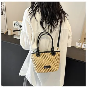 Detail of straw bucket bag with black leather trim and detachable shoulder strap