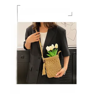 Detail of hand-woven hollow straw shoulder bag with stylish fringe and wooden beads