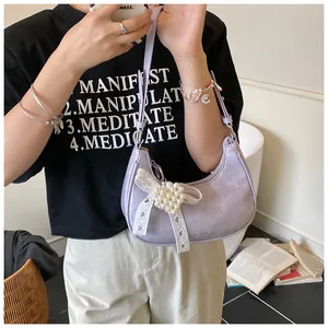 Detail of lavender crescent bag featuring white lace bow and dense pearl embellishments